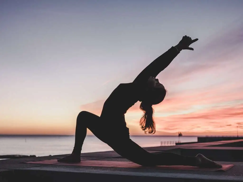 A yoga silhouette in a low lunge at sunset